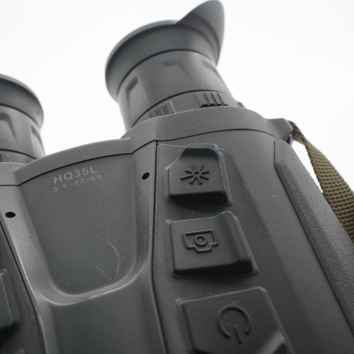 Close-up of a black binocular body with control buttons, showing the model marking 'HQ35L 0.5-22x60' and part of a tan strap against a white background.