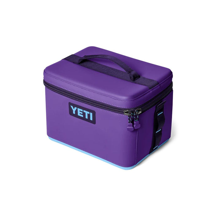 A purple YETI cooler bag with black handles and zipper pulls, featuring a black YETI logo patch on the front, set against a plain white background.
