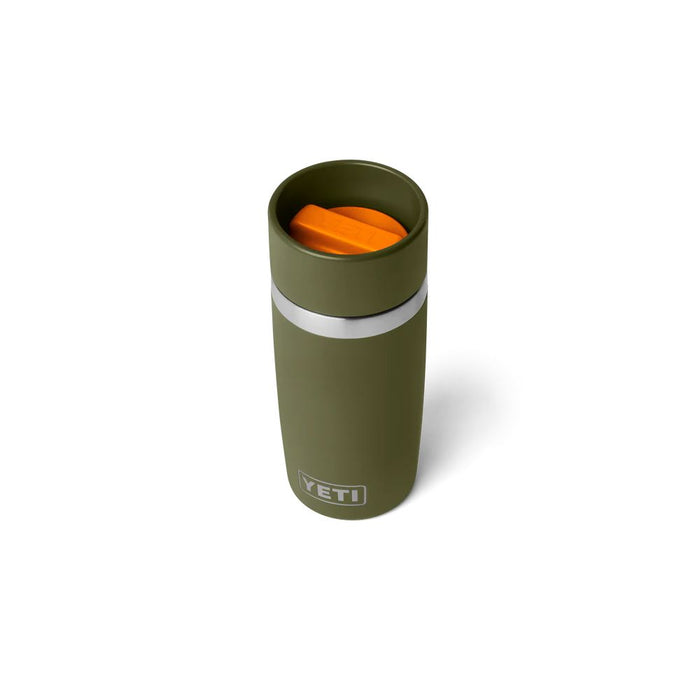 An olive green YETI travel tumbler with a silver band and an orange lid, shown on a white background.