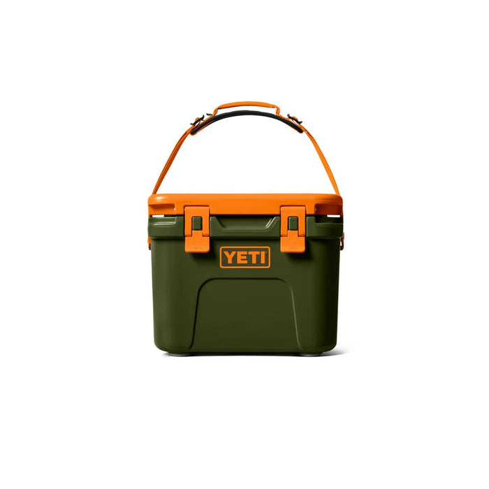 A YETI hard-sided cooler in dark green with bright orange accents, including the handle, latches, and front logo badge, shown on a clean white background.